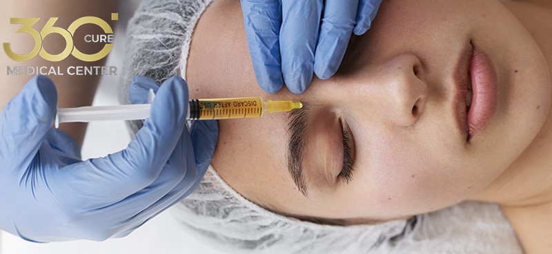 طبيب جلدية يحقن إبرة نضارة في خد سيدة بمركز 360 كيور الطبي في أبو ظبي